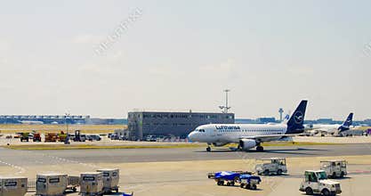 Frankfurt, Germany - May 2, 2023: Lufthansa airline service vehicles drives near plane. Lufthansa airline plane going on