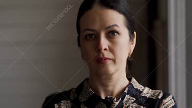 Close-up of a serious woman looking at the camera from home. housewife tired after cleaning, coking, and other work at
