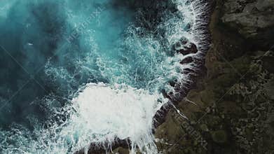Top view Ocean Waves Crashing on Rocky Shoreline. Drone Shot. Aerial view of frothy ocean waves crashing against a