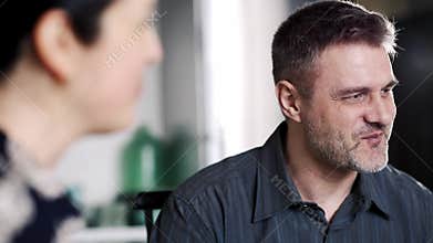 Happy father smiling and looking at wife. Satisfied husband listen wife and daughter. Man satisfied talking at dining