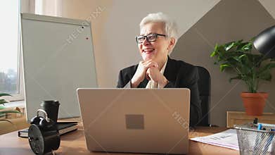 Middle aged senior woman boss leader discussing with team in online meeting. Older mature businesswoman in office speak