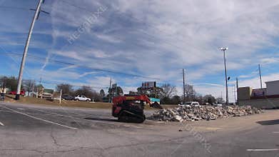 Bobcat dumping rocks in a pile in a parking lot of a new Harbor Freight tools