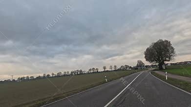 Car ride to the horizon between fields and meadows and clouds