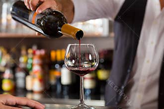 Red wine pouring in glass at bar