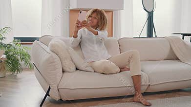 Woman sitting on couch taking selfie