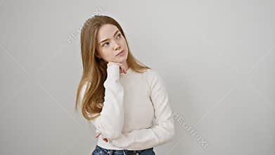 Young blonde woman wearing sweater standing serious face thinking about question with hand on chin, thoughtful about confusing