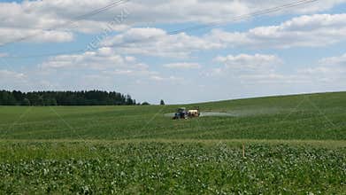 Tractor moves through a field and sprays fertilizers to protect the plants from insect or pest attacks