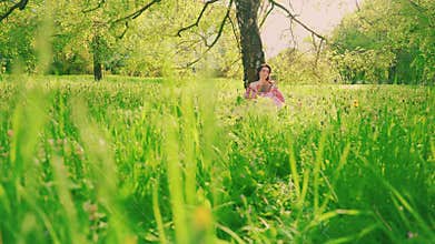green grass close-up silhouette woman sitting under tree reading old paper book hands holding novel art. Summer garden