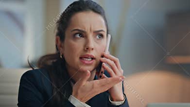 Stressed businesswoman speaking phone gesturing hand at office desk closeup