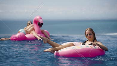 Happy woman chill in infinity pool with inflatable donut rubber ring