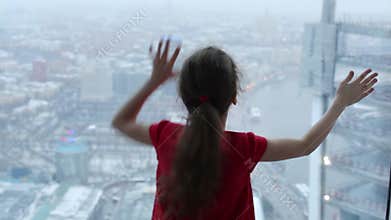 Back of little girl in red touching glass of