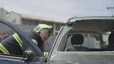 A courageous firefighter, equipped with specialized tools, heroically rescues people trapped in a car accident