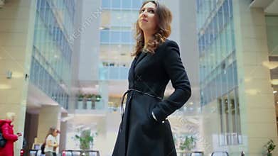 Young woman in dark cloak walks around in hall of