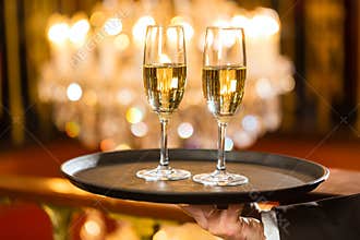 Waiter served champagne glasses on tray in restaurant