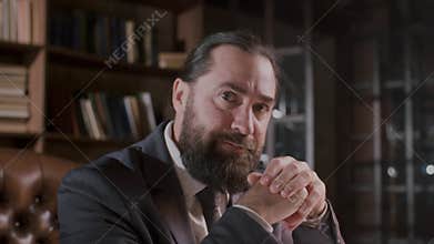Bearded businessman analyzing documents in the office with focus and seriousness for his career