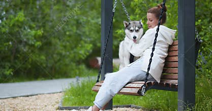 Nature's embrace: A young woman cuddles her Husky amidst the park's beauty.