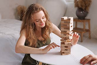 two women playing Jenga board game at home, excitement and relaxation, mind development concept,