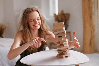 two women playing Jenga board game at home, excitement and relaxation, mind development concept,