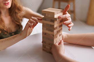 two women playing Jenga board game at home, excitement and relaxation, mind development concept,
