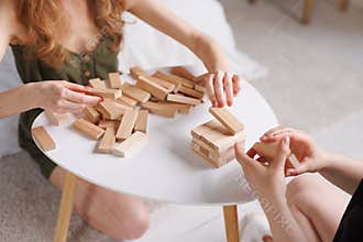 two women playing Jenga board game at home, excitement and relaxation, mind development concept,