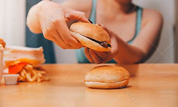 Binge eating disorder concept with woman eating fast food burger, fired chicken , donuts and desserts