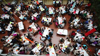 A spacious hall with tables and many young people,
