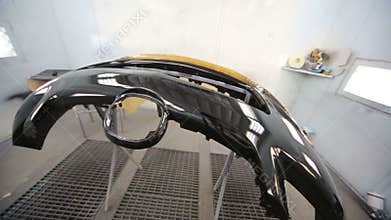 Painted bumper in painting booth at car service