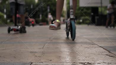 Children riding scooters along a vibrant city pathway in the afternoon