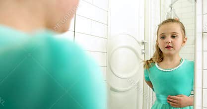 Young Girl is Curiously Gazing at Herself in the Mirror, Joyfully Exploring Her Reflection with Pure Innocence