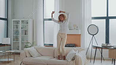 Woman jumps on couch in modern apartment
