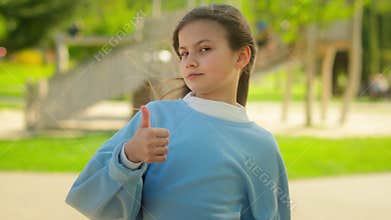 Caucasian little girl child kid female orphan schoolgirl pupil adopted daughter look at camera outdoors city park smile