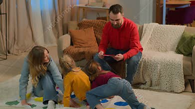 Caucasian happy family parents children playing game twister at evening home together holiday funny carefree kids little