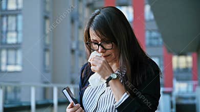 Mature woman coughing into a napkin, outdoor