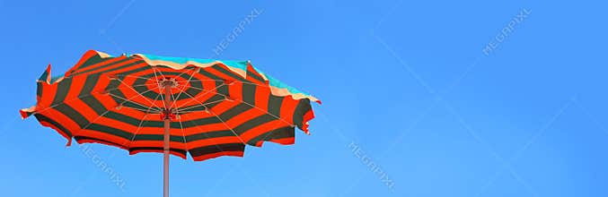Umbrella beach banner. Panoramic view of colorful beach umbrella on a sunny beach day. Banner, lots of copy space.
