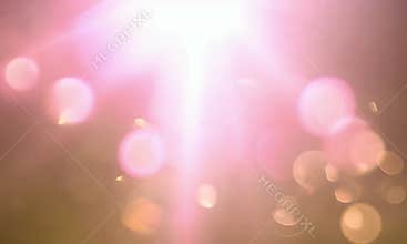 A pink and gold lens flare emitting a glowing effect, with shimmering bokeh.