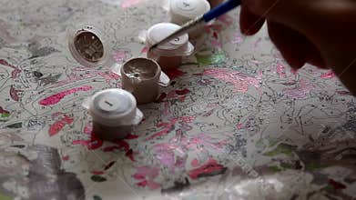 Aspiring artist amateur diligently and paints neatly with a brush, choosing from palette