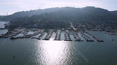 Aerial sweep over Sausalito revealing dense marina docks, boats, and hillside residences with the San Francisco skyline in the