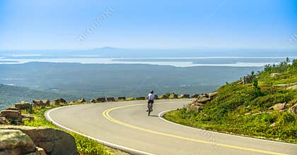 Female mountain bike cyclist riding downhill along Cadillac Mountain road in Acadia National Park