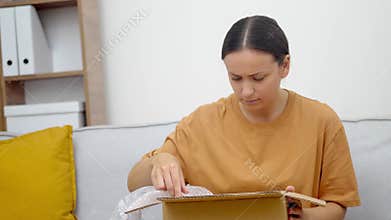 Dissatisfied woman finds defect in goods in box with filling for safety of package with delivery