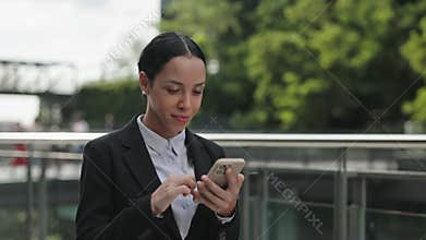 Attractive Busy Young Woman Standing in the Street and Scrolling Device in Formal Clothes.