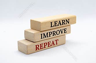 Learn, Improve and Repeat text on wooden blocks with white cover background. Improvement and development concept