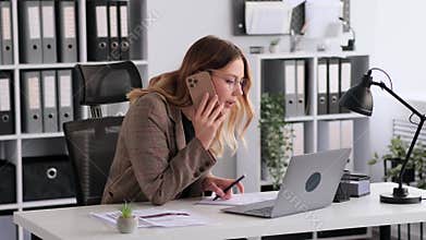 Office Worker Talking Phone With Client And Using Laptop