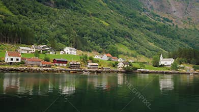 A picturesque village with traditional wooden houses on the shore of the fjord in Norway. View from a floating cruise