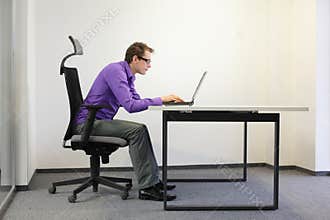 Shortsighted businessman bad sitting posture at laptop