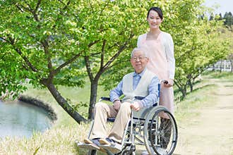 Senior man sitting on a wheelchair with caregiver