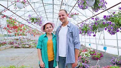 A family of aspiring flower sellers stands in a greenhouse,