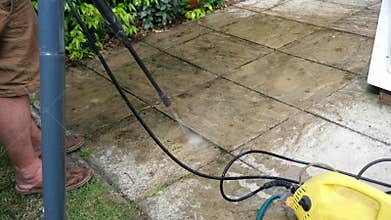 Cleaning terrace with high-pressure water blaster, cleaning dirty paving stones