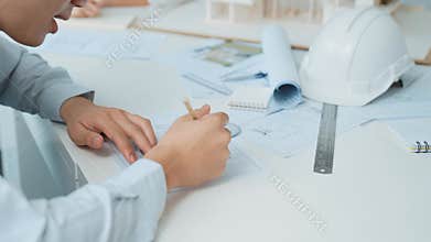 Skilled engineer draws blueprint on meeting table with blueprint. Immaculate.