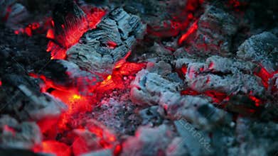 Flicker of smoldering embers lay in ashes, closeup