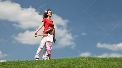 mother and daughter standing on meadow holding